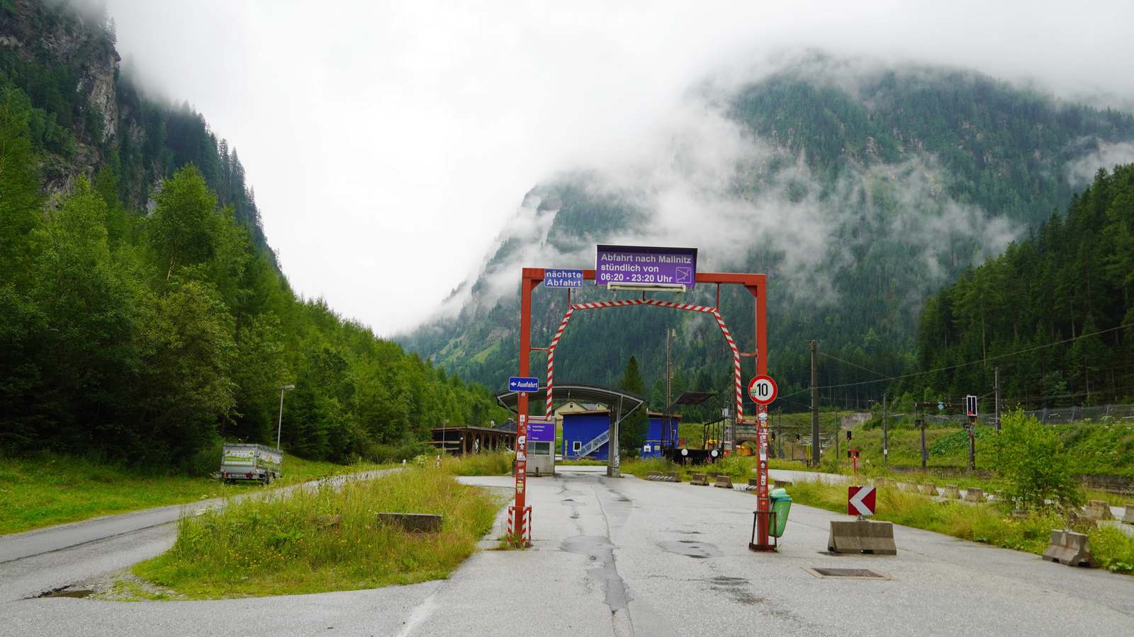 Entrance to the Tauernbahn car shuttle at Böckstein station with a departure sign for Mallnitz and mountains behind