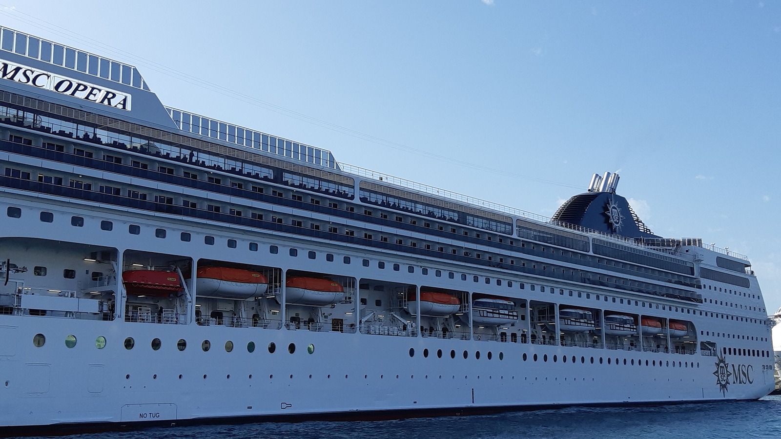 MSC Opera docked at Funchal, Madeira, with its name on the superstructure and lifeboats along the hull