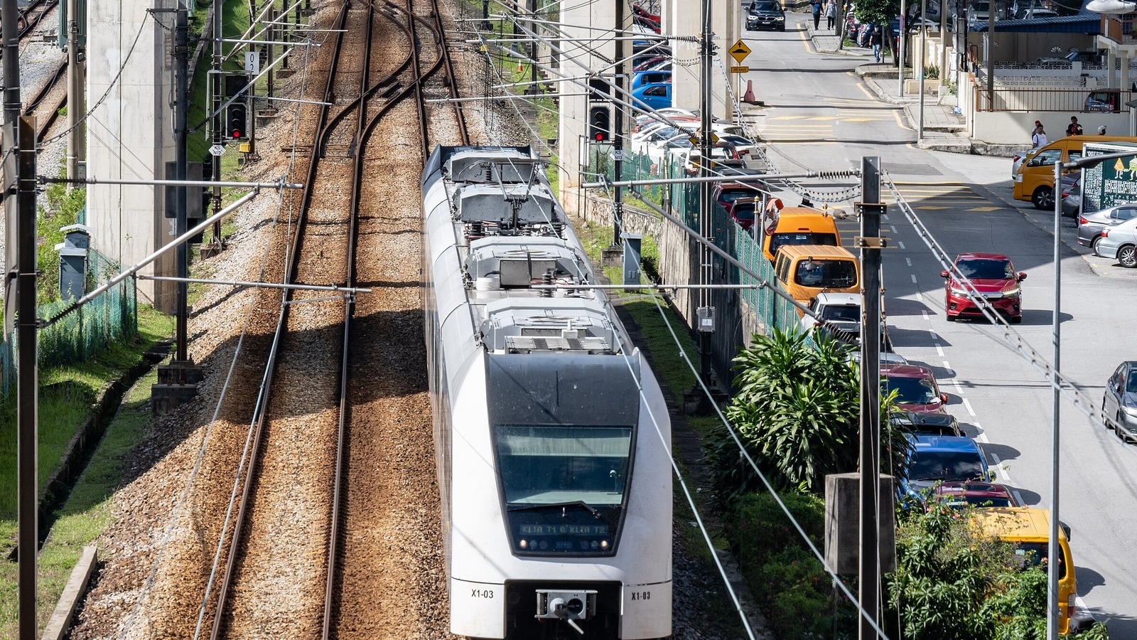 A white KLIA Ekspres Siemens Desiro train signed for KLIA Terminal 1 and Terminal 2 running along the line at Bangsar in Kuala Lumpur