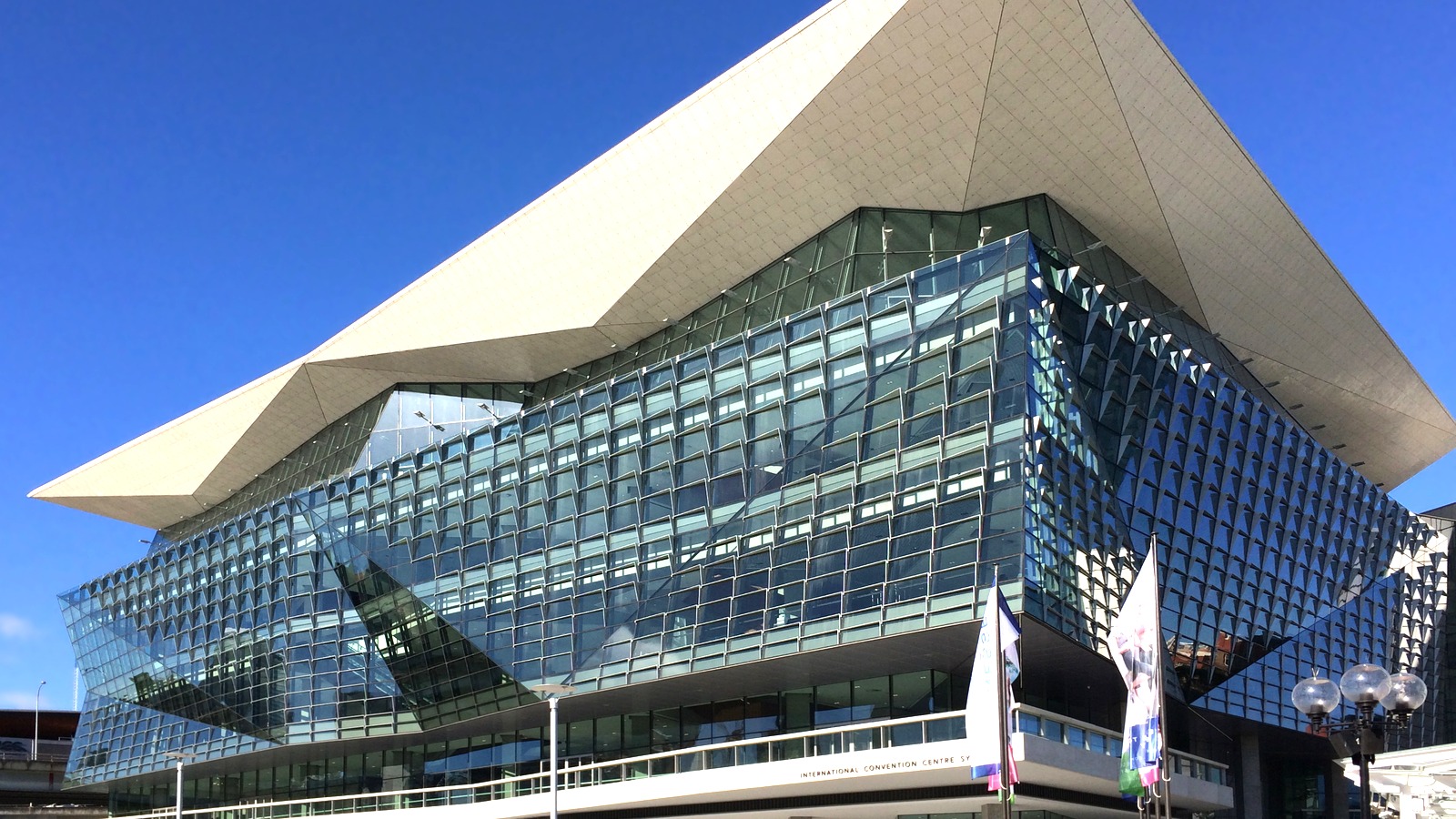 Daylight exterior of the glass ICC Sydney convention block on Darling Harbour, the Travel Expo venue.