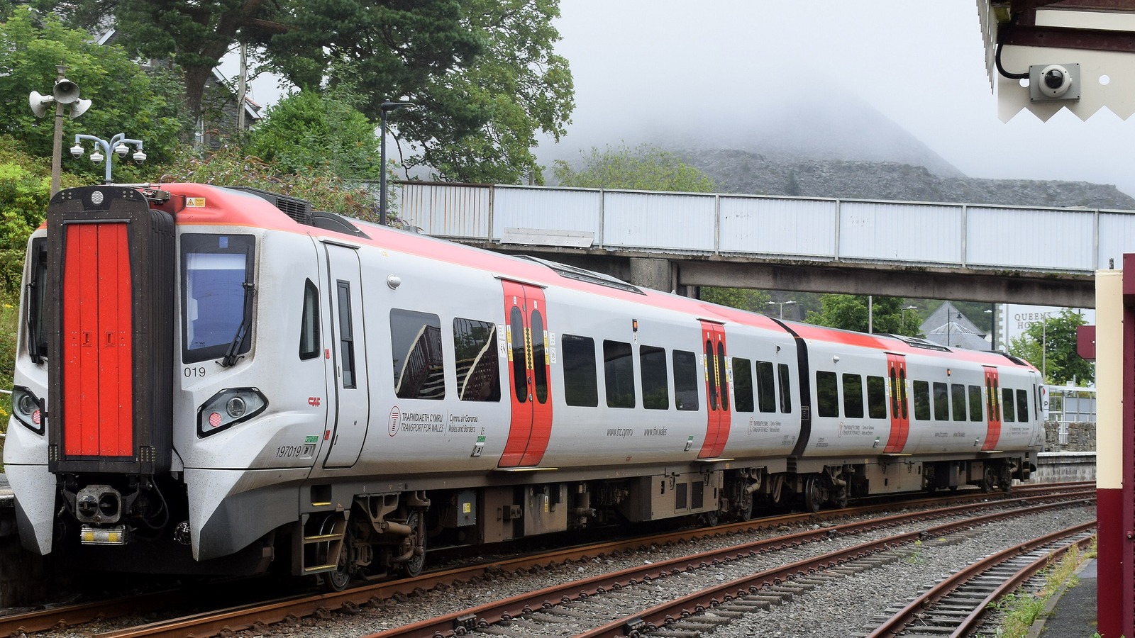 Transport for Wales Class 197 train at Blaenau Ffestiniog station on the Conwy Valley line with misty hills behind