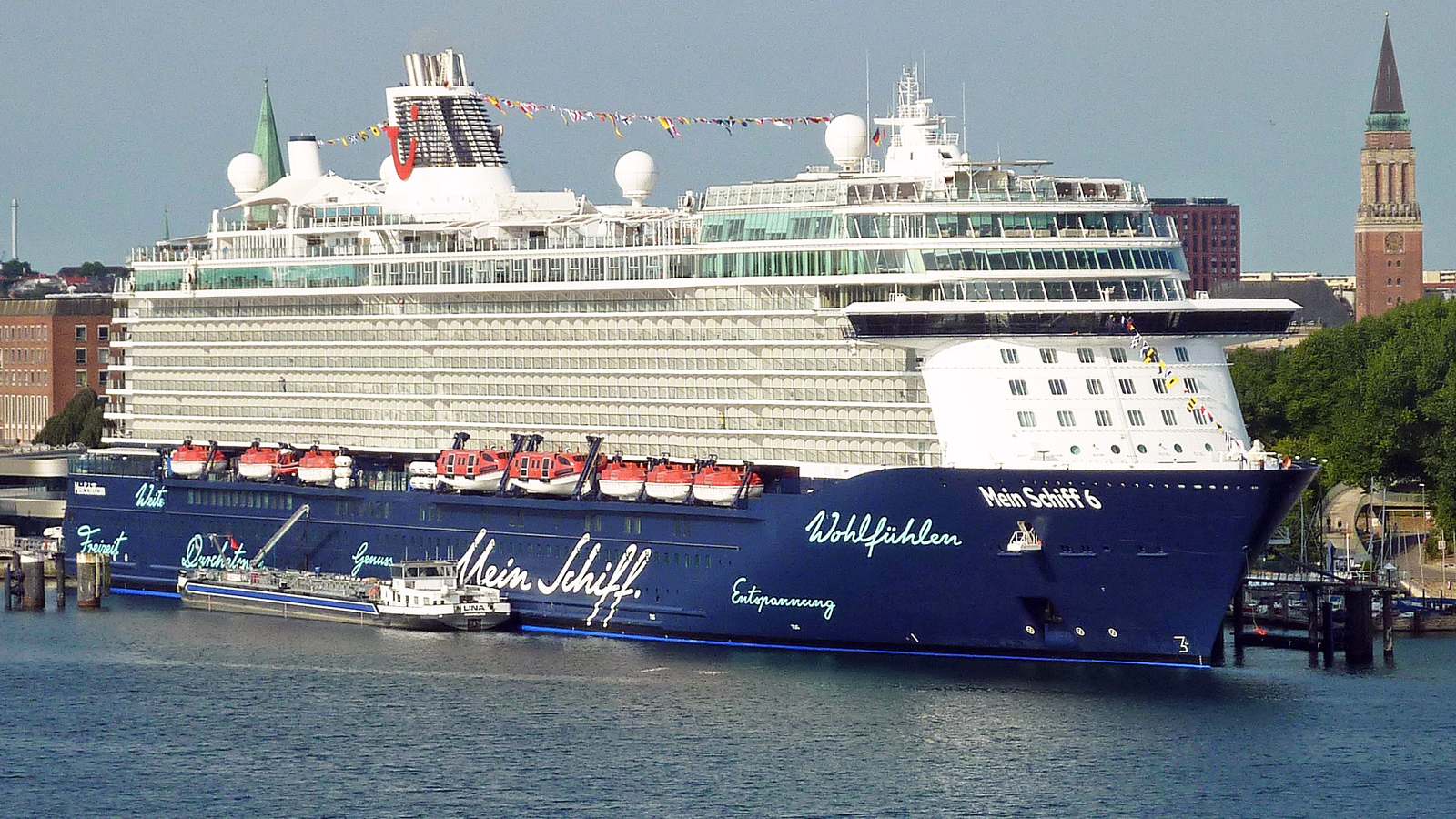 Cruise ship Mein Schiff 6 berthed in Kiel with the city skyline behind