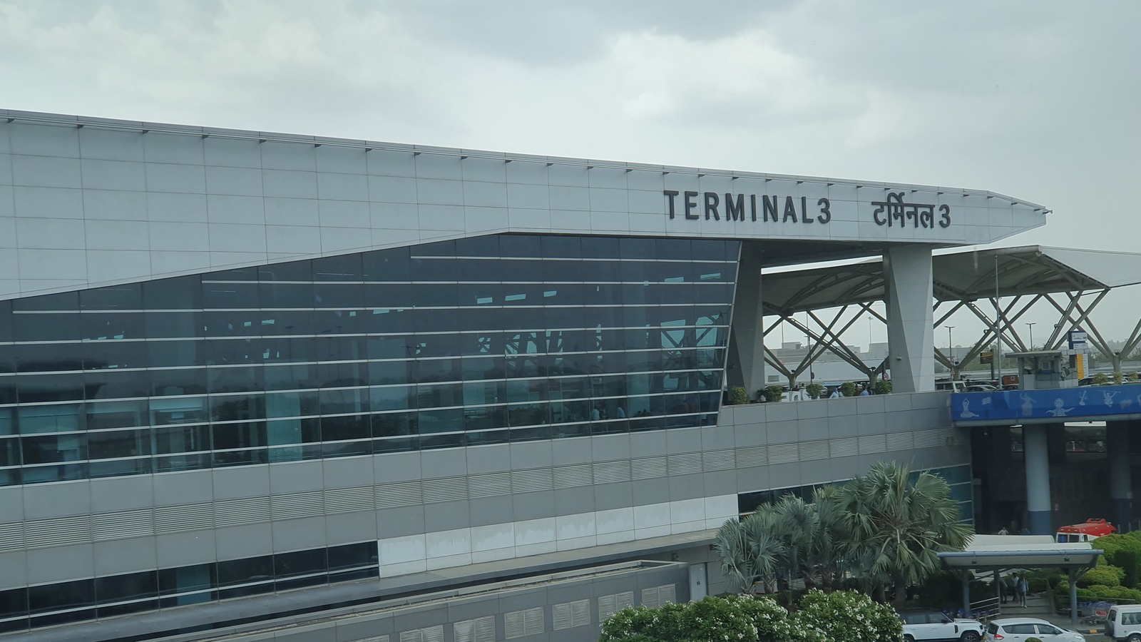Terminal 3 exterior at Delhi Airport with terminal signage above the glass facade
