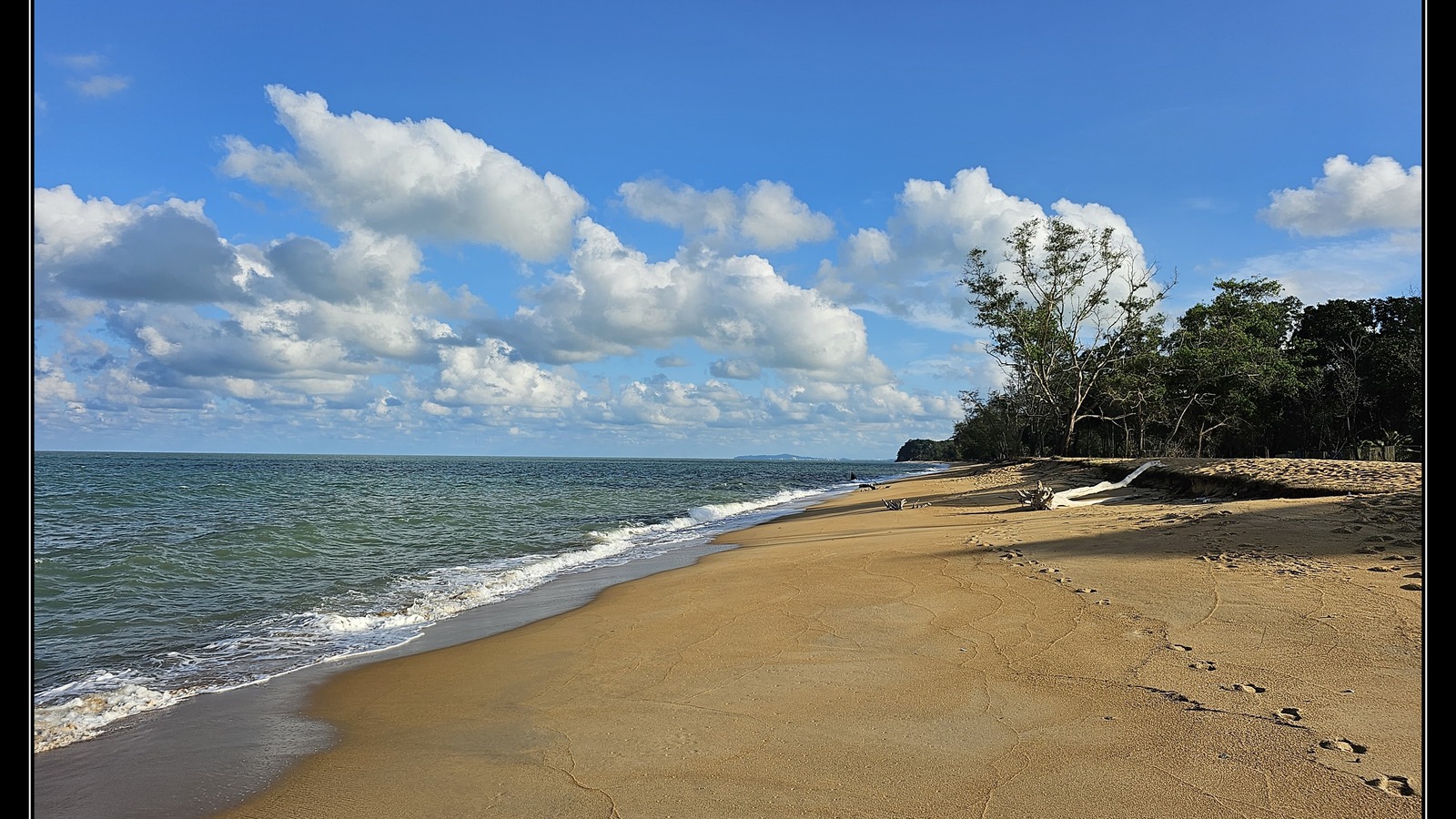 Cherating beach with the Club Med beachfront in the distance under a bright sky