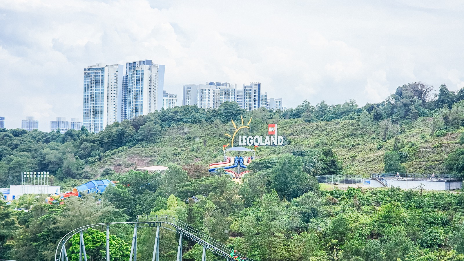LEGOLAND Malaysia hillside sign with water slides and coaster tracks in the background