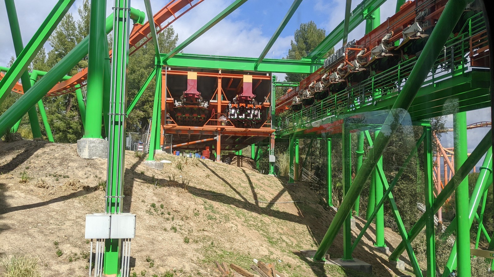 Orange Tatsu coaster train on green track at Six Flags Magic Mountain