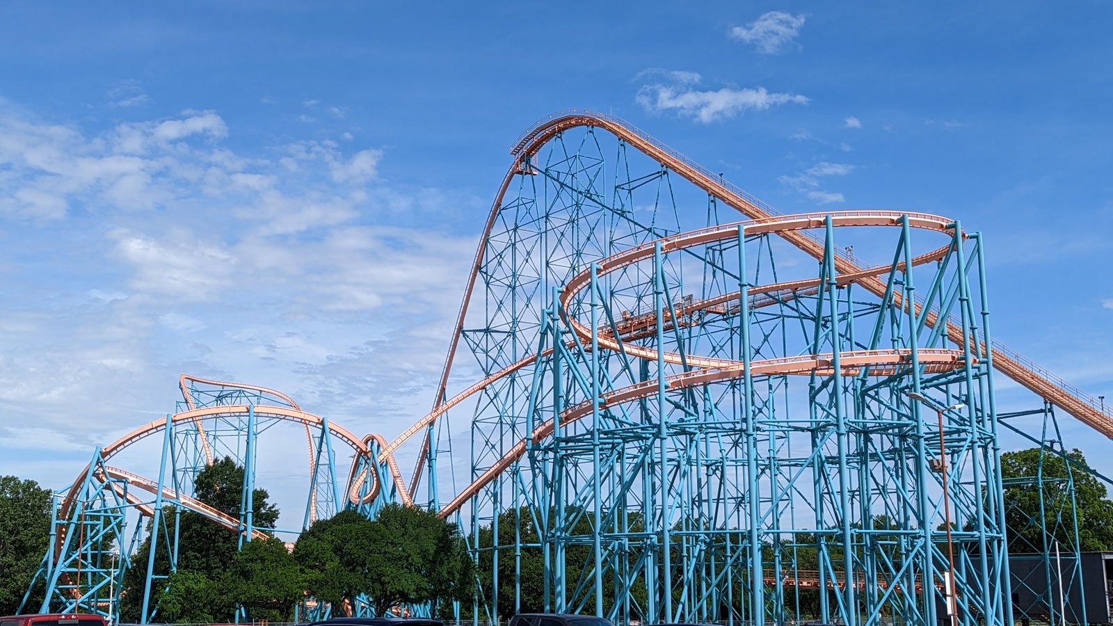 Titan's blue support structure and orange track rise over trees at Six Flags Over Texas